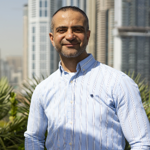 Marwan Nasry photographed against a skyline in Dubai wearing a button-up shirt and jeans.