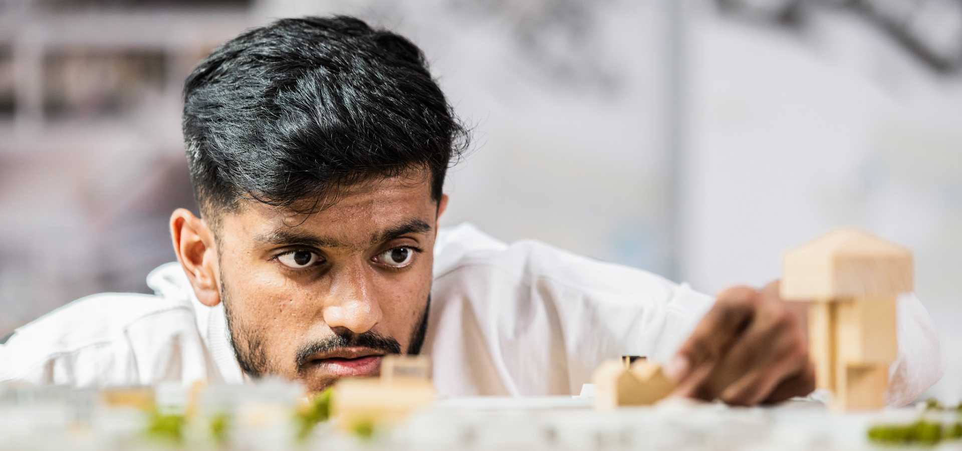 Photograph of an architecture student examining model buildings