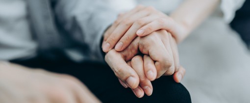 Two hands clutched together on top of the leg of one holder.