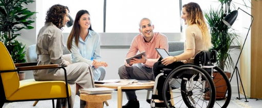Four people sat around a table, one using a wheelchair.