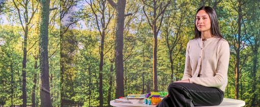 A female student sitting on chair in the Education building with legs crossed looking at camera