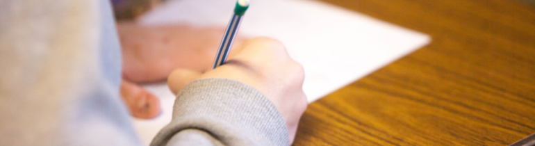 A student writing on paper with a mechanical pencil