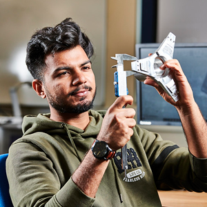 student sat measuring a machined part with a specialised measuring tool