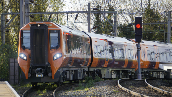 An orange West Midlands train turning into a station