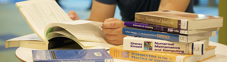 image of student with a pile of books doing research