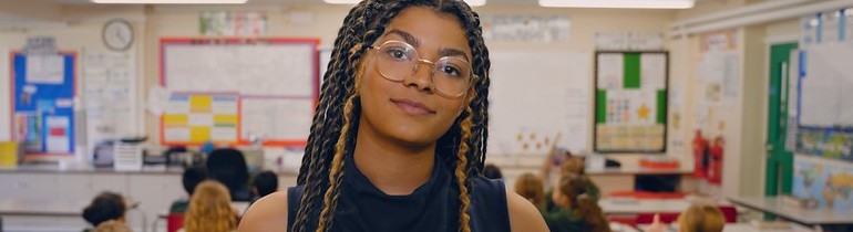 A student on a teaching placement, standing behind a classroom of children