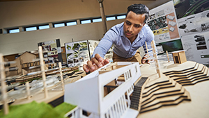 An architecture student at a table working on a sculpture