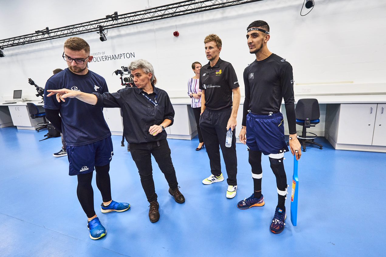 Sport students being instructed by a coach, wearing uniforms and working in the sports hall