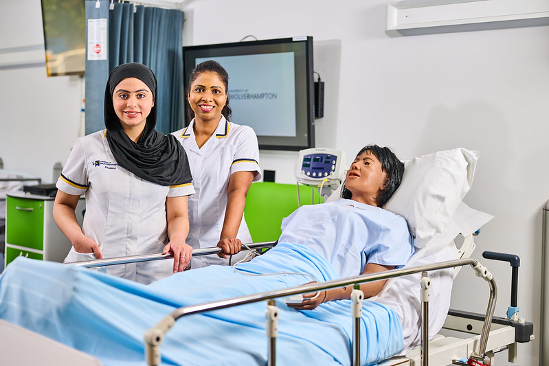 Nursing students at a medical bed in the nursing practical room.