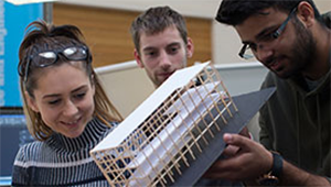 Three students at Springfield campus handling a miniature architecture model